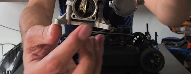 Mi mano con el cárter abierto del motor Traxxas 3.3, el cigüeñal a la vista, y mi coche de pista atrás
